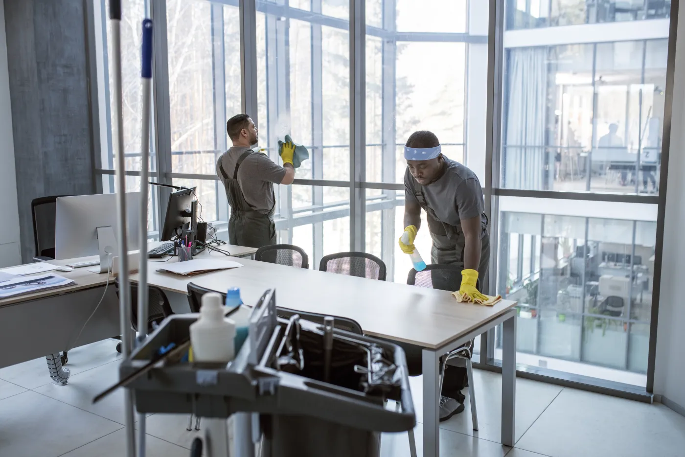 Cleaning crew detailing windows and desks in a commercial office