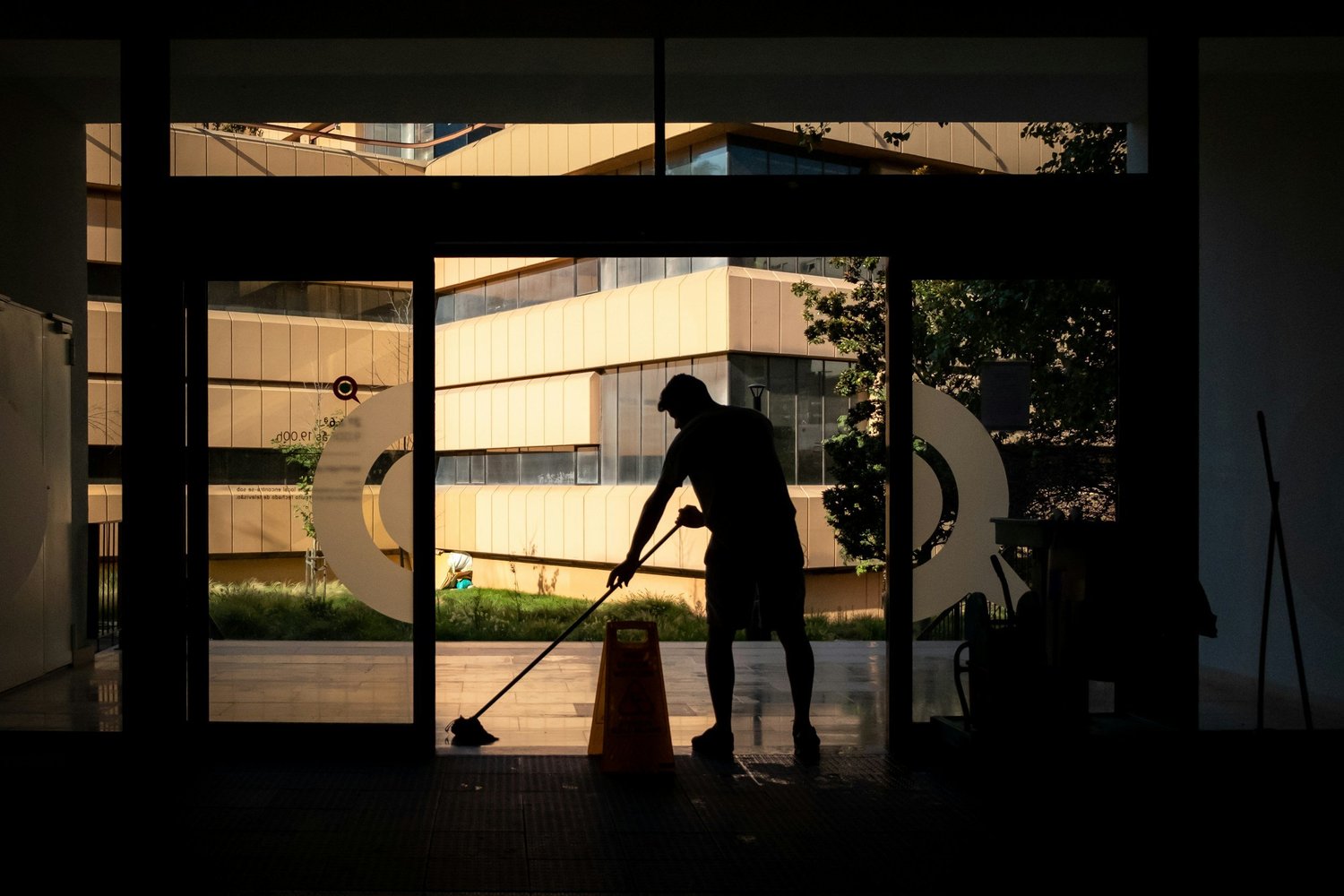 Commercial cleaner mopping a building entrance in the evening